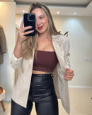 Blazer bege claro, selfie mostrando interior aberto; caimento solto ao quadril, botão discreto e mangas ajustadas ao pulso.