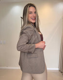 Blazer marrom-claro com padronagem discreta em espinha, caimento alongado até o quadril, lapela tradicional, bolso de aba e mangas com três botões no punho.