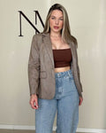 Blazer marrom herringbone visto inteiro, caimento reto na altura do quadril com bolsos de aba frontais e lapela em V.